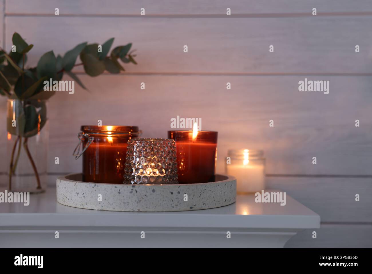 Burning candles on mantel near white wall indoors Stock Photo Alamy