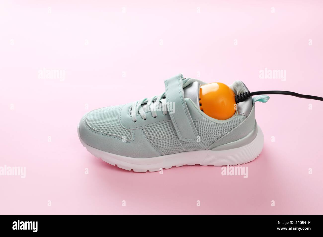 Stylish sneaker with modern electric shoe dryer on pink background