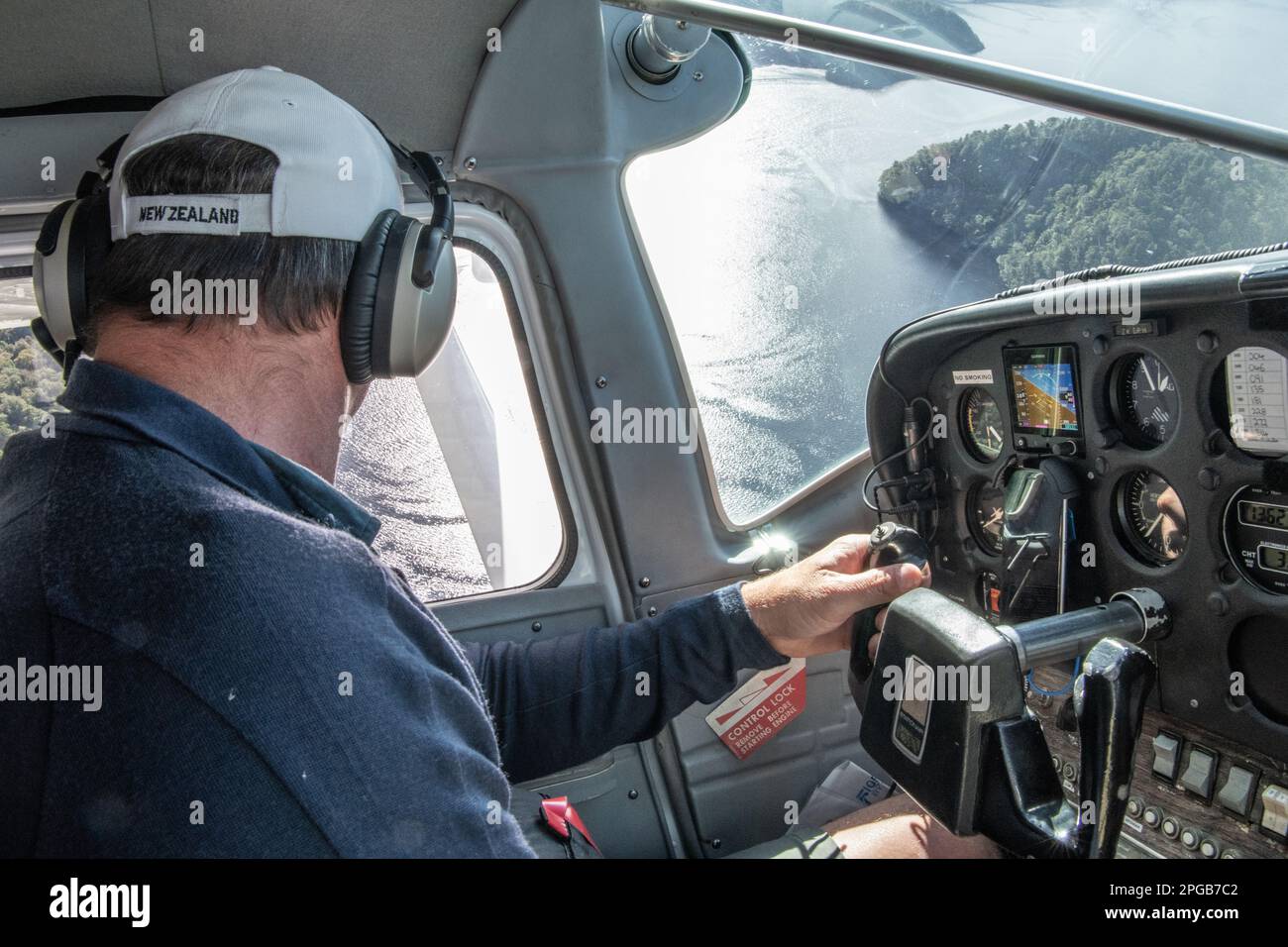 Pilot looking out the window of a seaplane as he looks for a place to land the aircraft on the pacific ocean in Fiordland National Park, New Zealand. Stock Photo