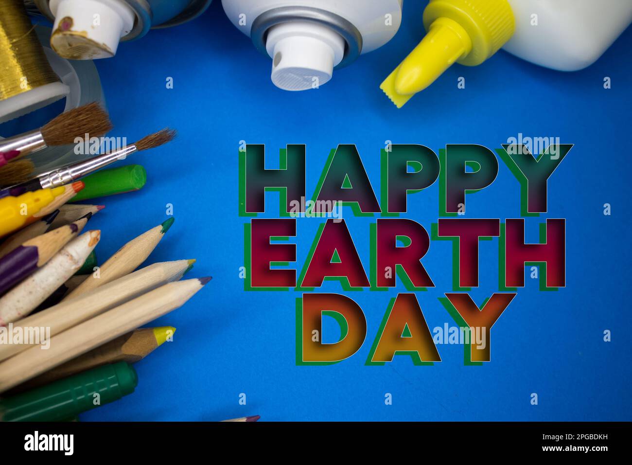 Overhead shot of school supplies with Earth Day text. Brushes, pencils, artistic tools. Art And Craft Work Tools. Stock Photo