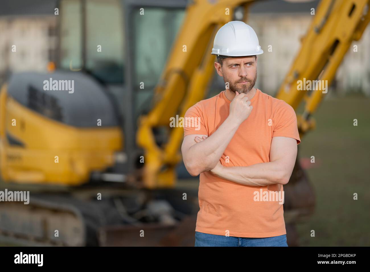 Worker in helmet on site construction. Man excavator bulldozer worker. Construction driver worker with excavator on the background. Construction Stock Photo