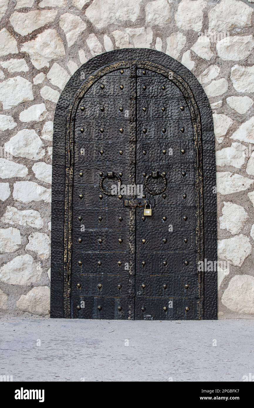 The black vintage metal gate locked on a stone wall Stock Photo Alamy