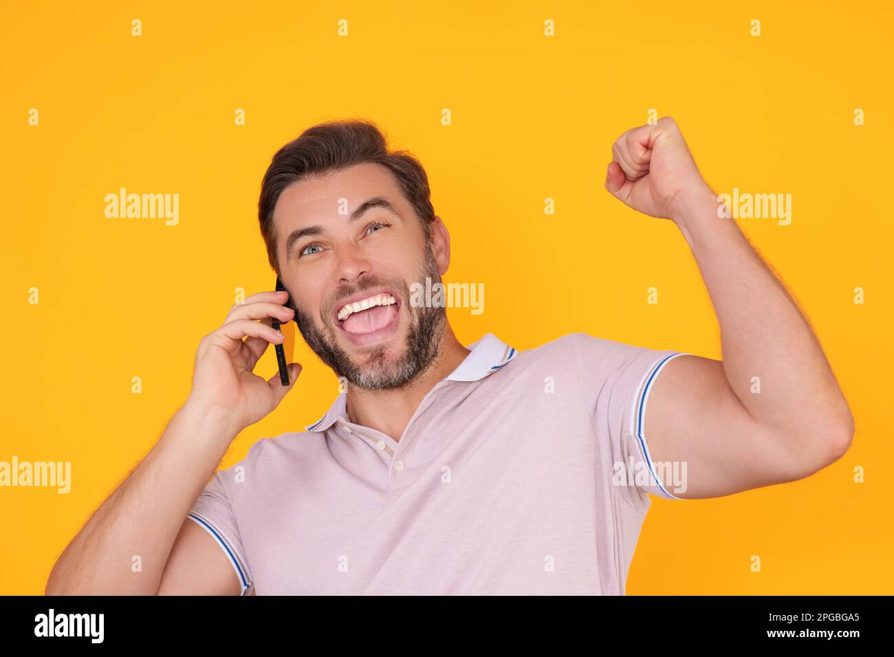 Excited man using smartphone, chatting, making post on social media. Guy call on phone isolated over studio background. Blogger talking on phone Stock Photo