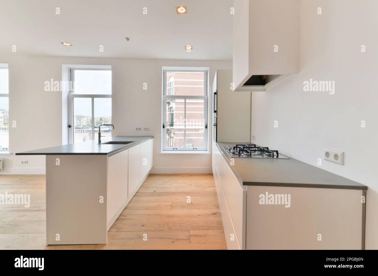 an empty kitchen with wood flooring and white cabinets in the photo is ...