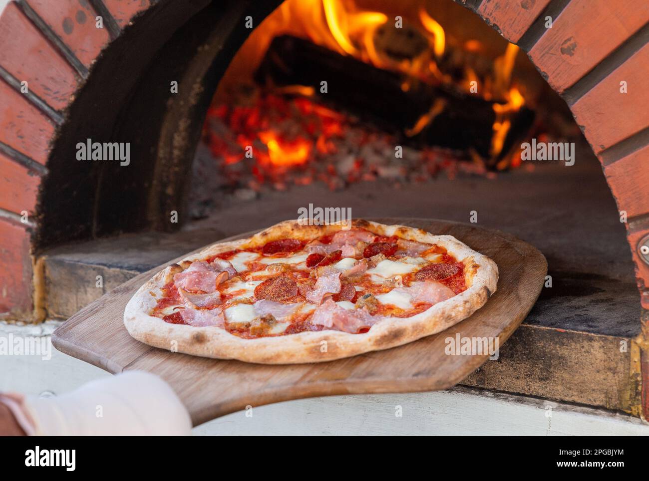 Chef placing pizza in brick oven to be cooked Stock Photo Alamy