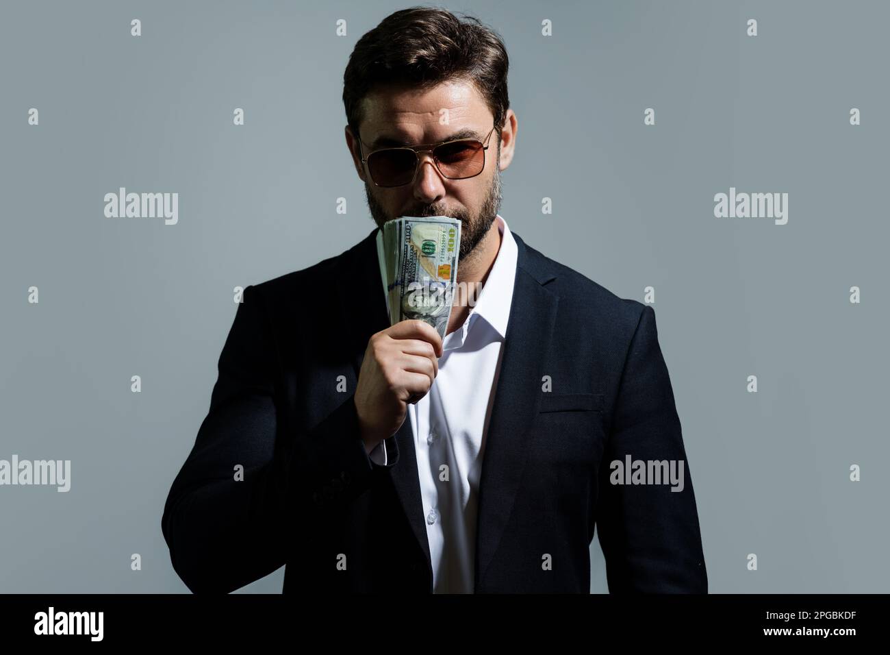 Man showing cash money in dollar banknotes. Portrait of business man isolated on gray studio background. Successful winner celebrating success or Stock Photo