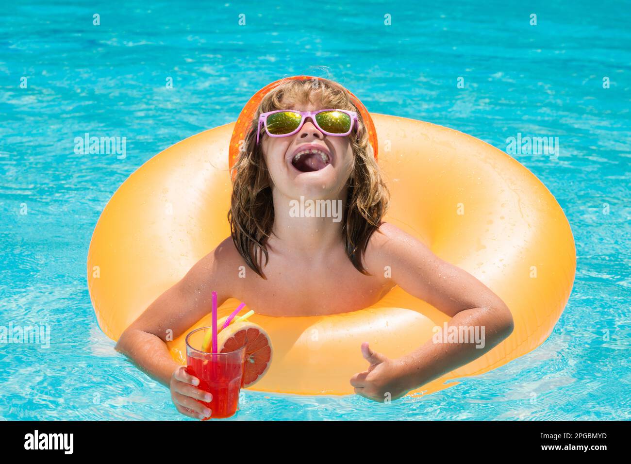Child swim in pool in summer day, drink juice cocktail. Summer holidays and vacation concept. Kids swimming and playing in a pool. Vacation in a Stock Photo