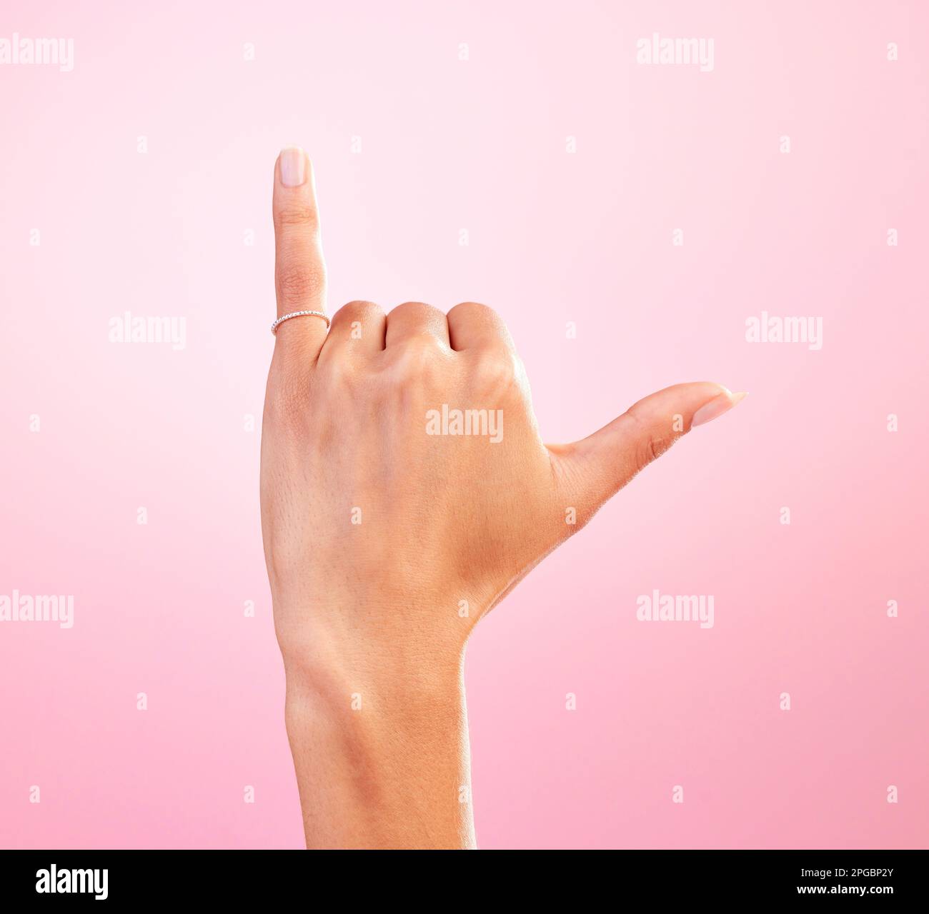 Woman hand, shaka and studio with a icon, emoji and hang ten surfing sign. Isolated, pink background and female hands showing winner, surf and Stock Photo