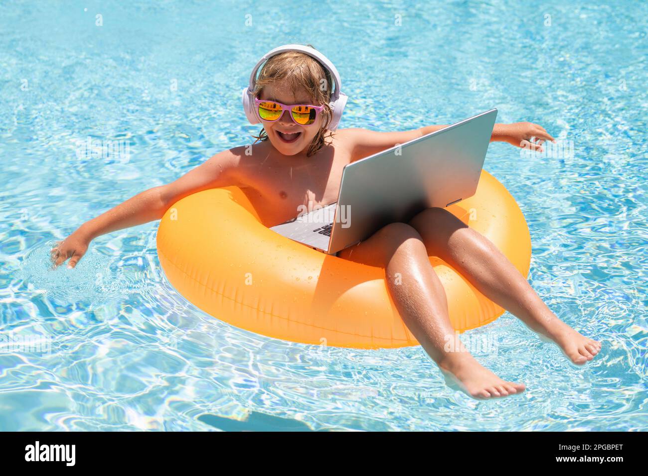 Kids working with laptop on summer vacation holidays. Little freelancer using computer, remote working in pool. Stock Photo