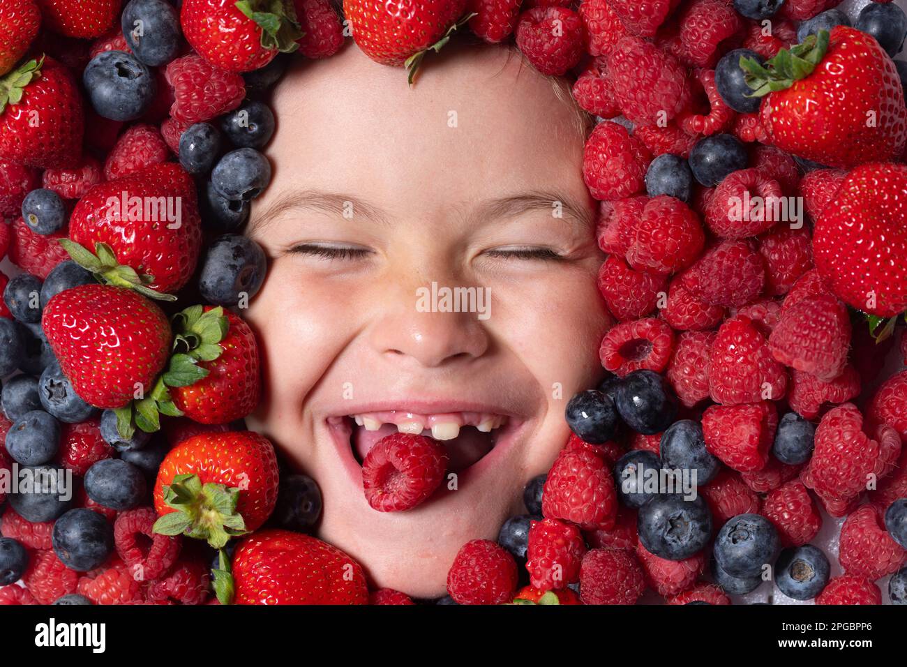 Healthy vitamins fruits. Mix of strawberry, blueberry, raspberry, blackberry background. Berries close up near kids face. Fresh berries, top view. Mix Stock Photo
