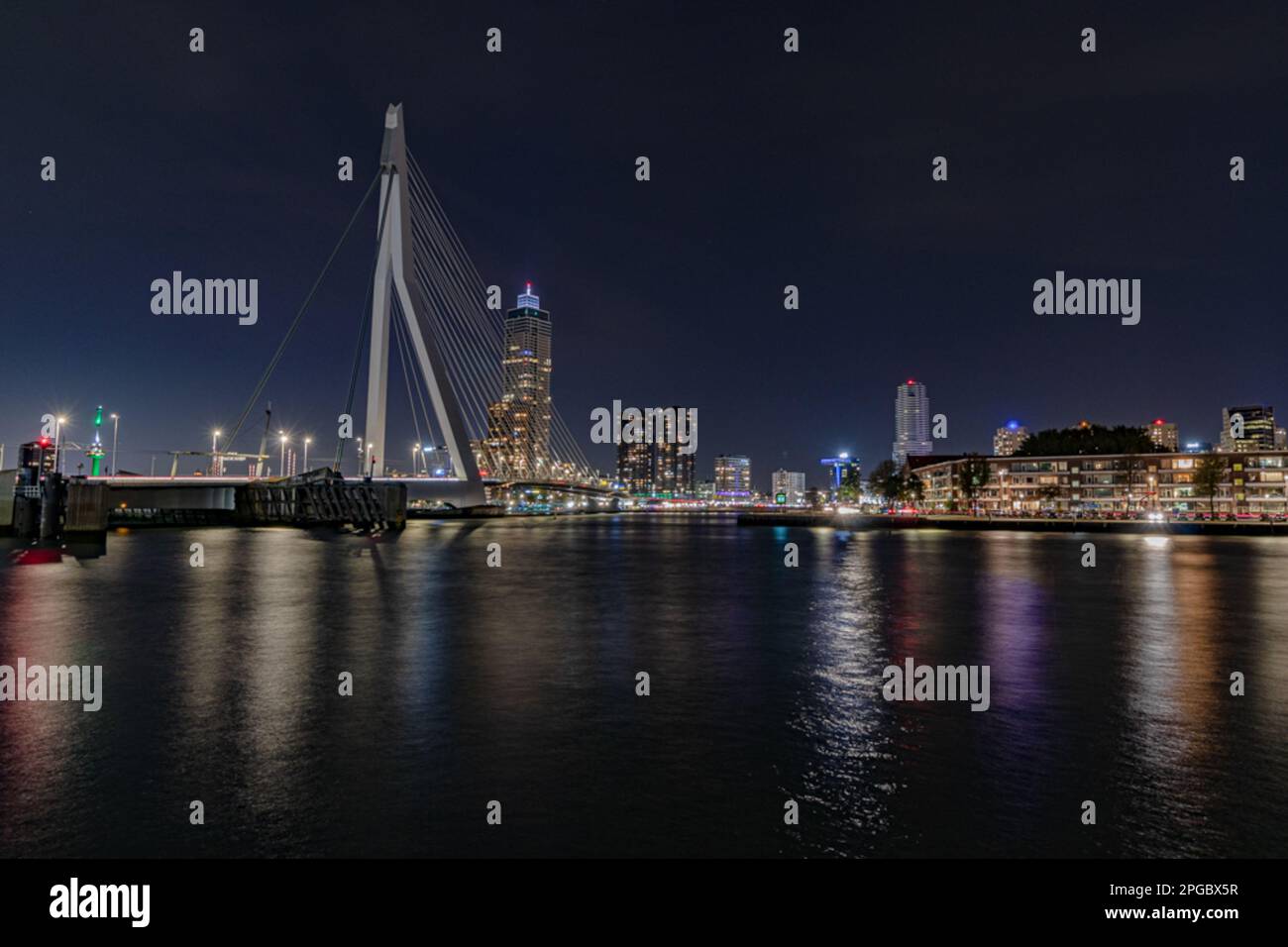 A vibrant city skyline at night, with a bridge spanning the water below ...