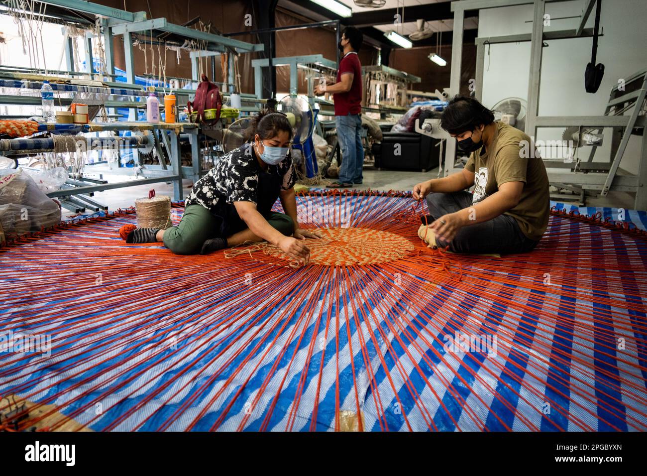 Bangkok, Thailand. 22nd Mar, 2023. Workers weave a large rug out of reused fabric and yarn waste