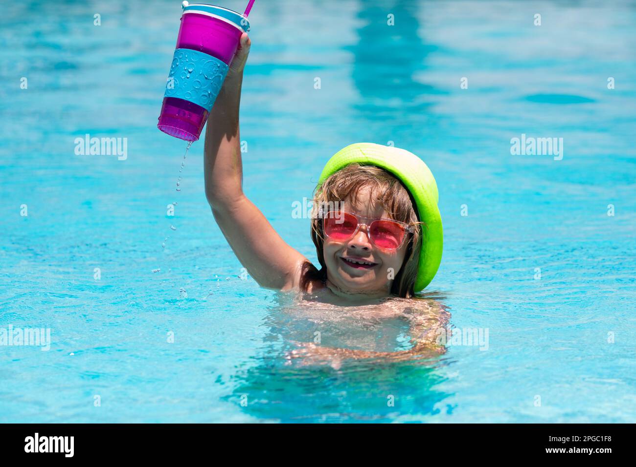 Cocktail in the pool. The child has a rest in swimming pool with a fruit drink. Summer vacation. Stock Photo