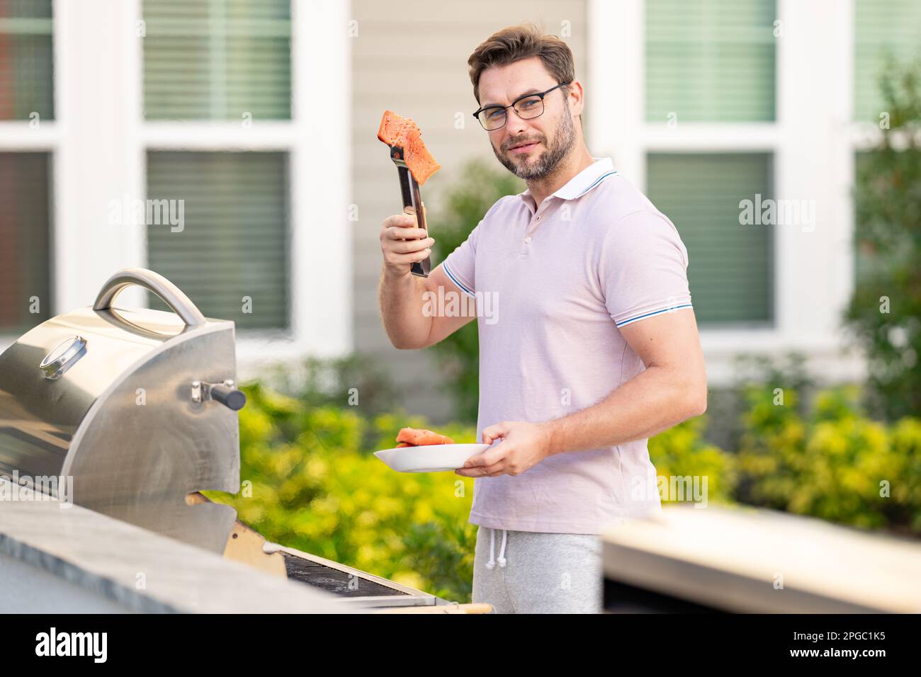Cook at a barbecue grill preparing salmon. Stock Photo