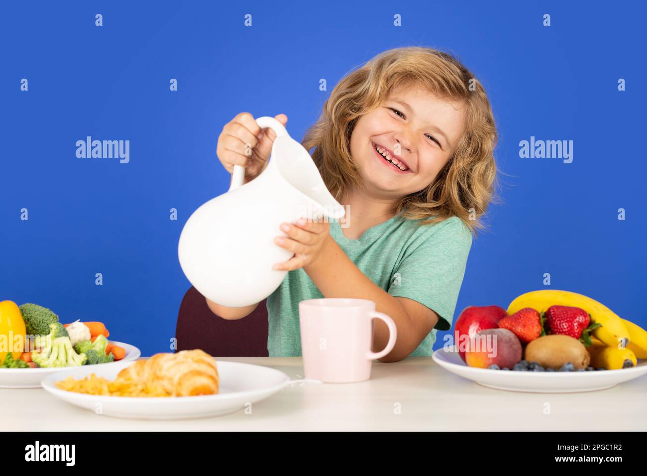 Child drink dairy milk. Cute kid drinking milk on blue background. Stock Photo