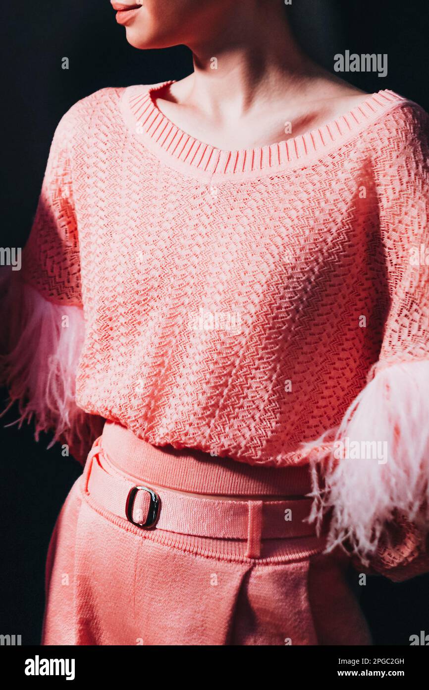 Cropped female figure in knitting pink stylish set sweater and pants on black background. Fashion details Stock Photo