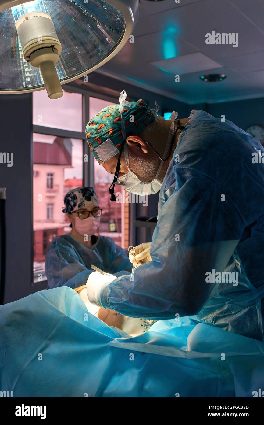 surgeon in the operating room is standing at the table with the patient ...
