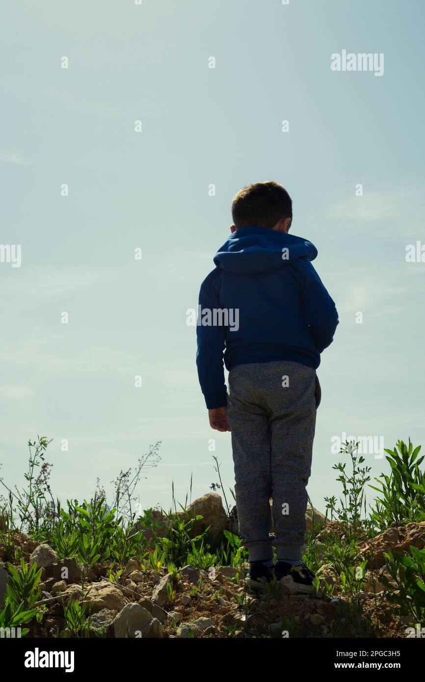 Rear view of boy standing on the hill Stock Photo - Alamy