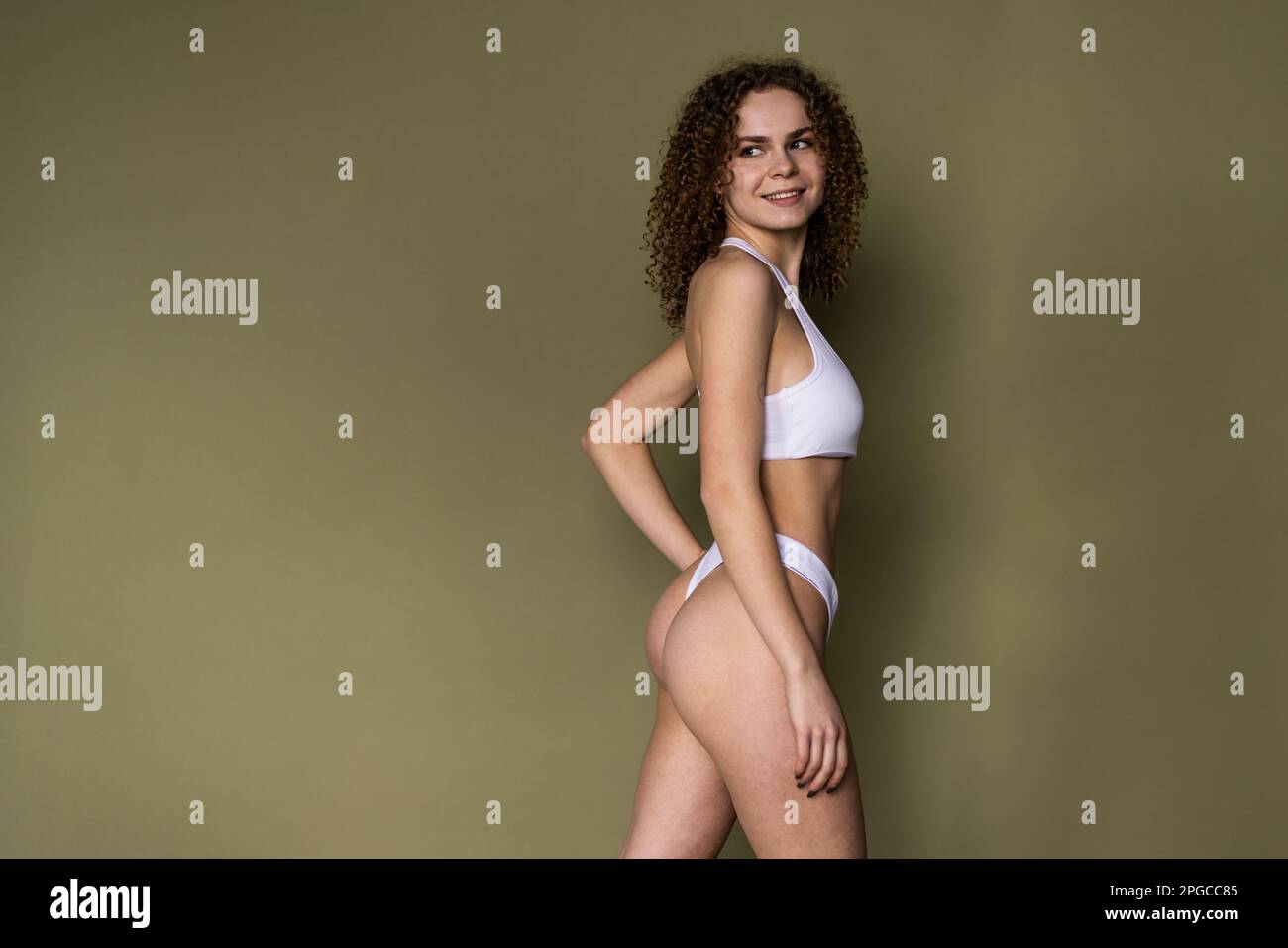 Young woman with perfect sport body in white lingerie on khaki background Stock Photo