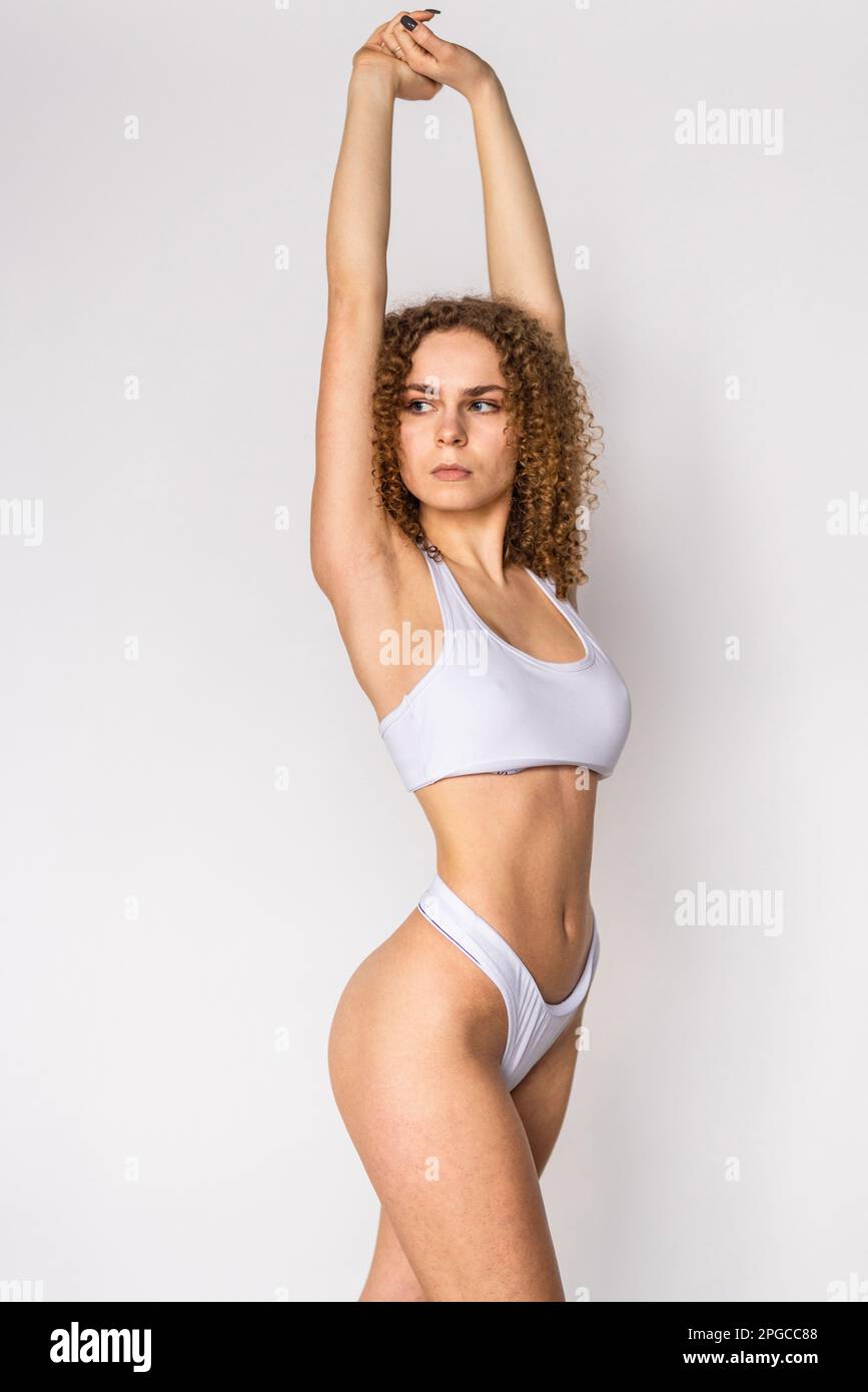Young woman with perfect sport body in white lingerie isolated on gray background Stock Photo