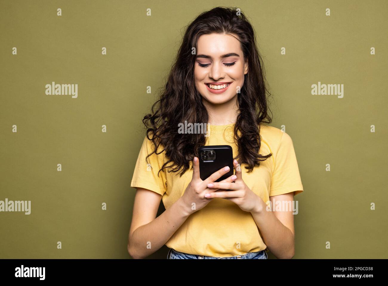 Young woman hold in hand use mobile cell phone typing read message isolated on khaki background studio portrait. People lifestyle concept Stock Photo