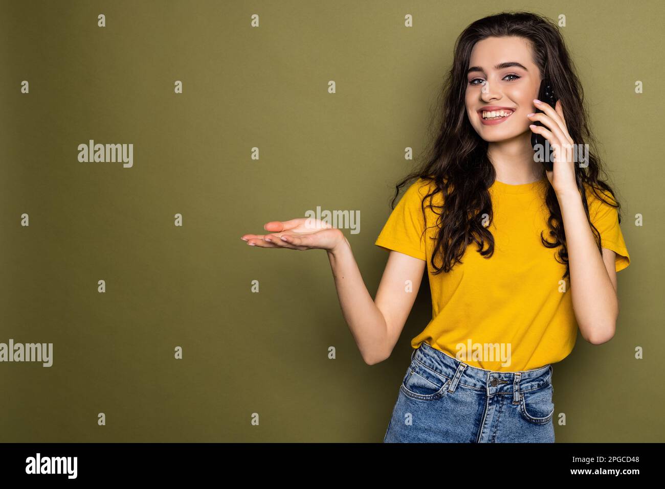 Young woman talk speak on mobile cell phone conducting pleasant conversation isolated on khaki background studio portrait. People lifestyle concept Stock Photo