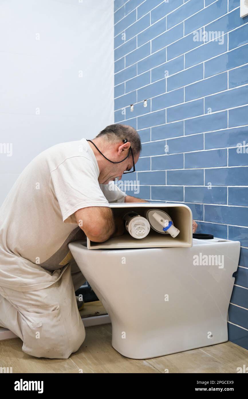 Senior plumber installer installing toilet cistern Stock Photo Alamy