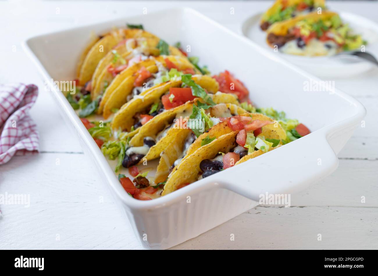 Tacos with ground beef, kidney beans, cheese, tomatoes and lettuce in a