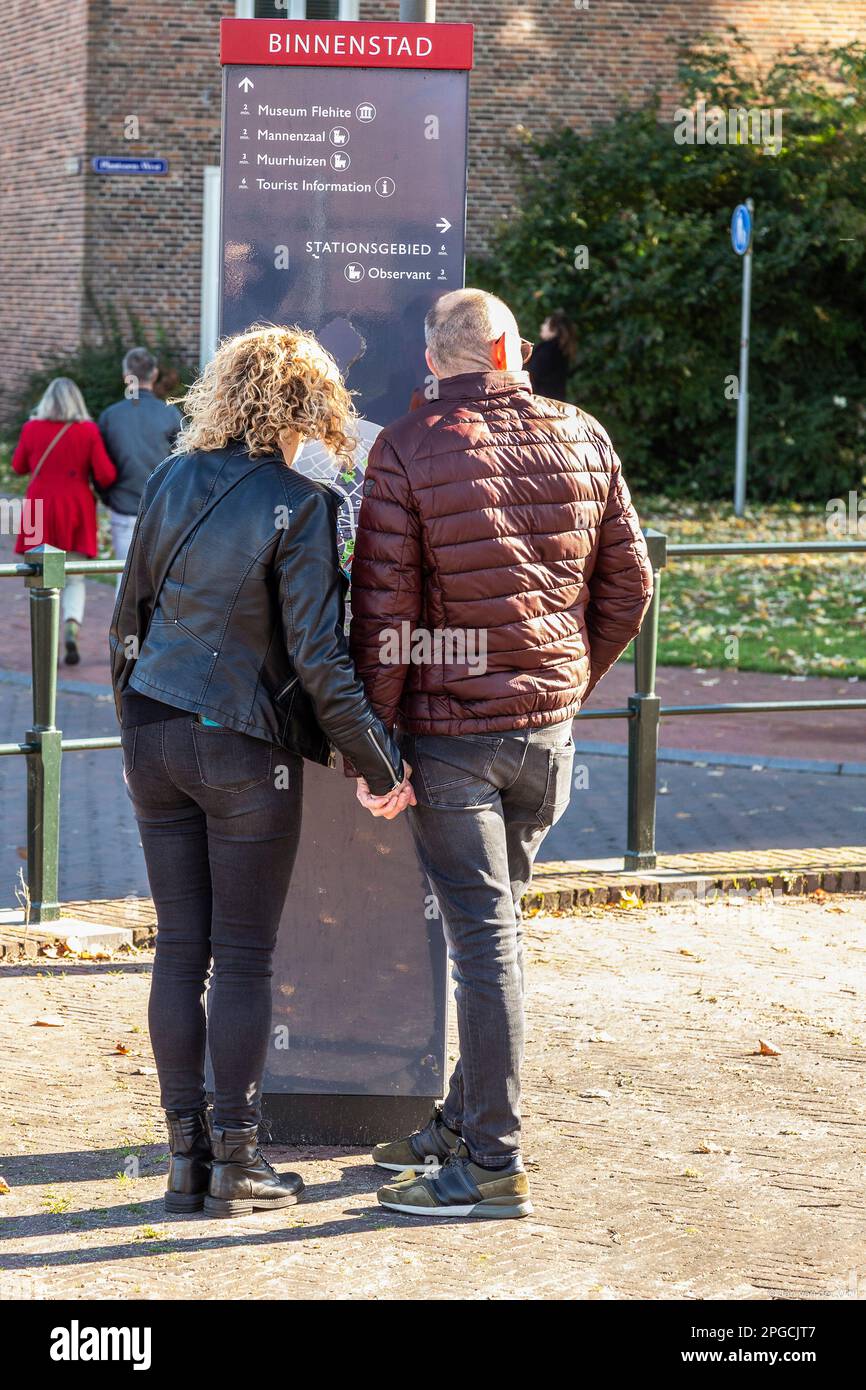 People look at a city tourist information board on the street in Amersfoort. Stock Photo