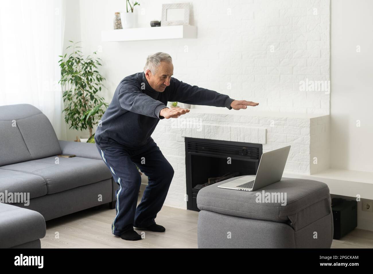 Gray-haired senior man doing online training on a laptop Stock Photo