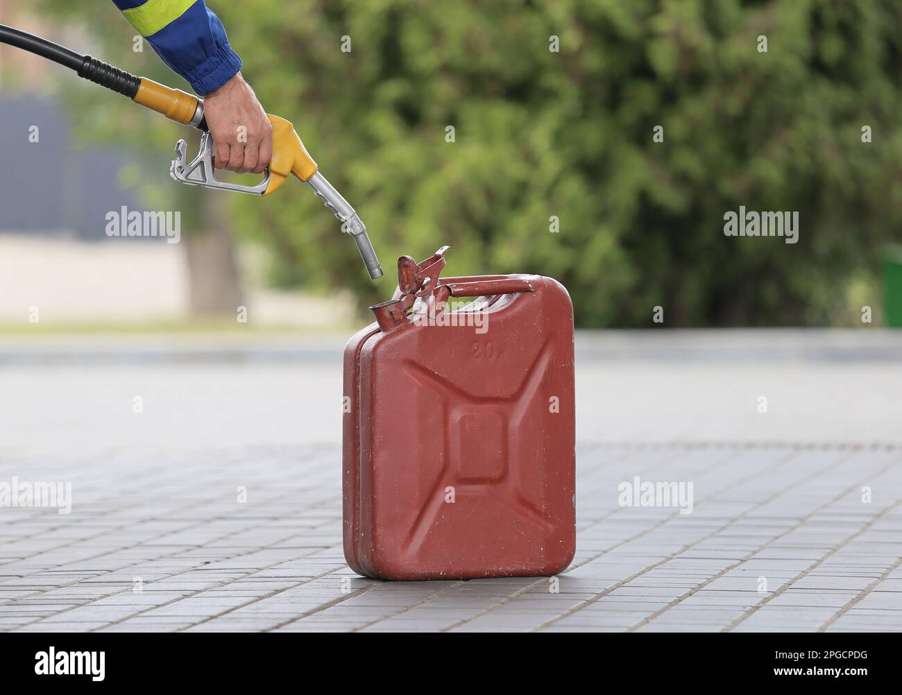 A man fills jerry cans at a gas station. A man fills gasoline in a