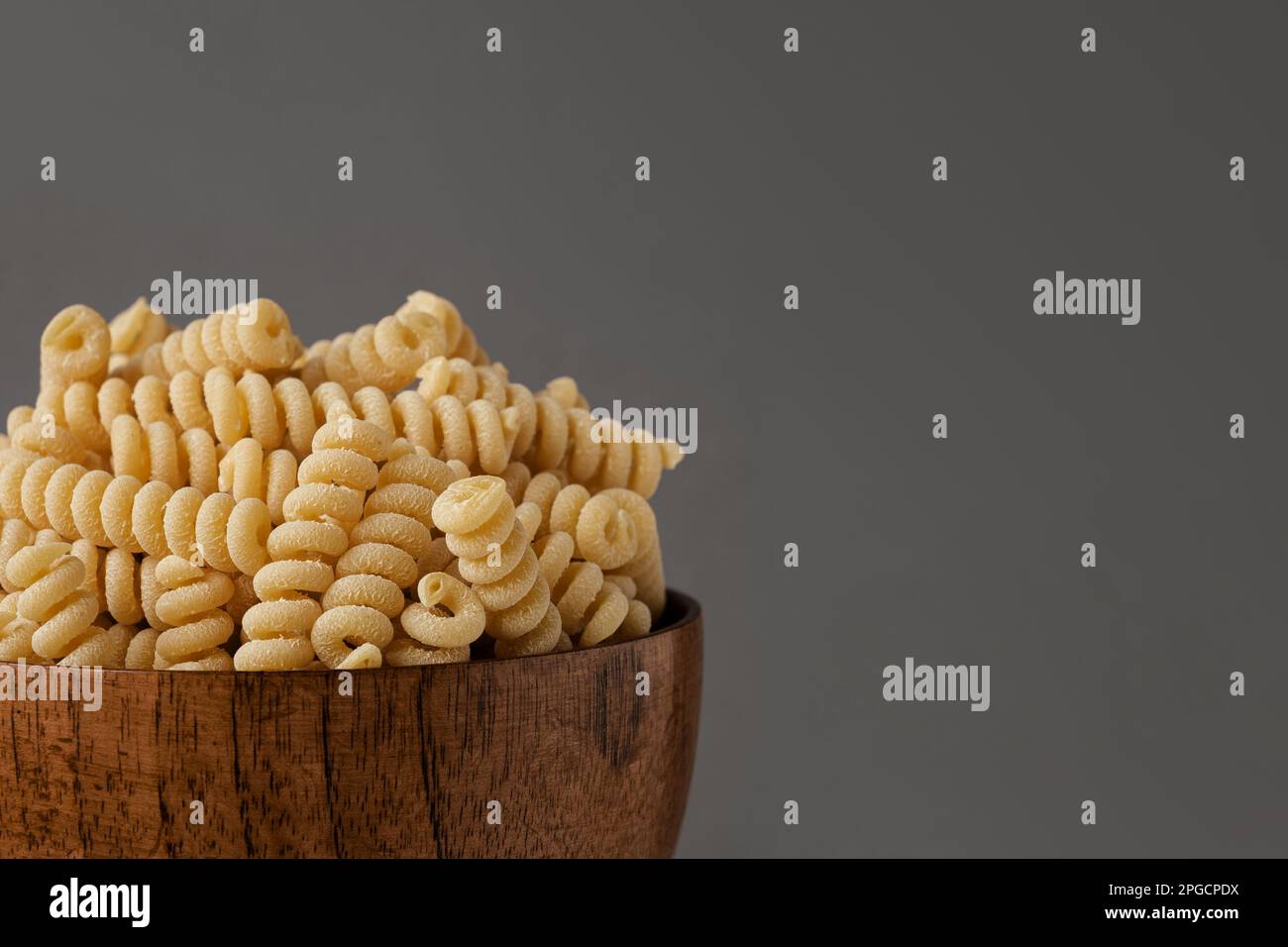 Gluten Free Cornmeal Pasta in wooden Bowl. Spiral Raw Macaroni from