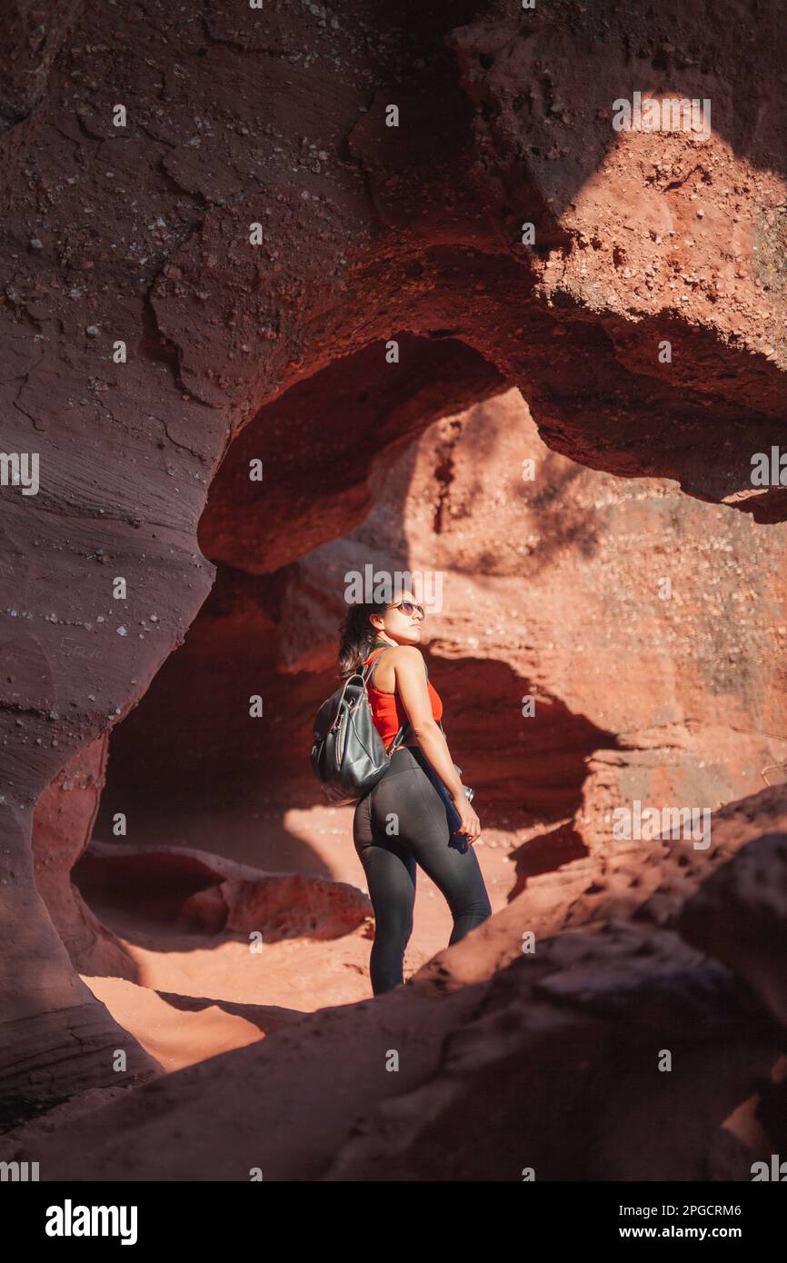 From below back view of female tourist in casual clothes with backpack exploring famous Red Canyon Stock Photo