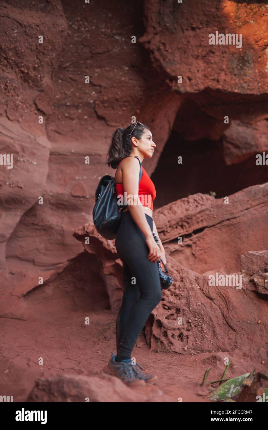 From below side view of female tourist in casual clothes with backpack exploring famous Red Canyon looking away Stock Photo