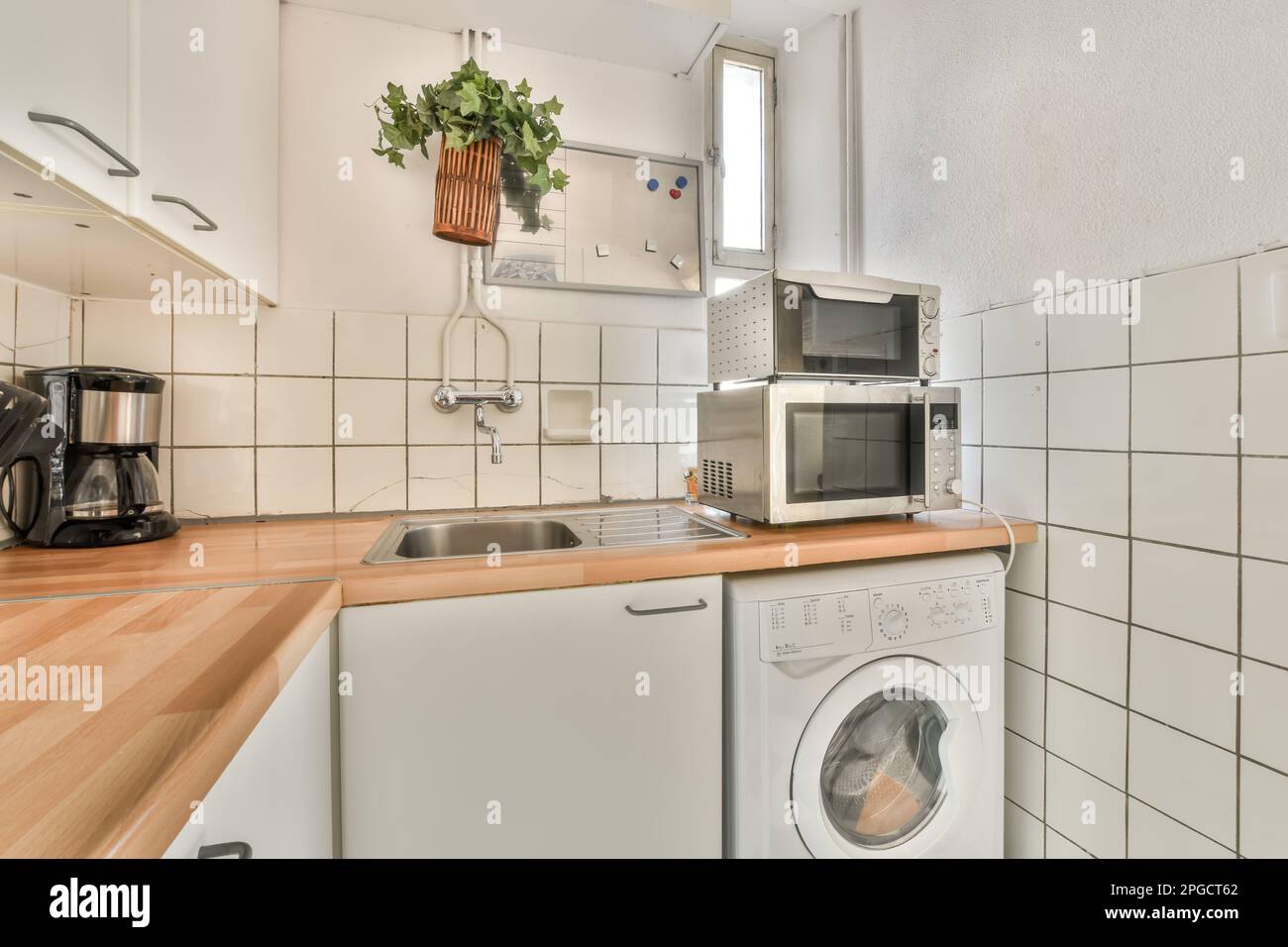 Microwave ovens placed on washing machine near sink and gas stove in