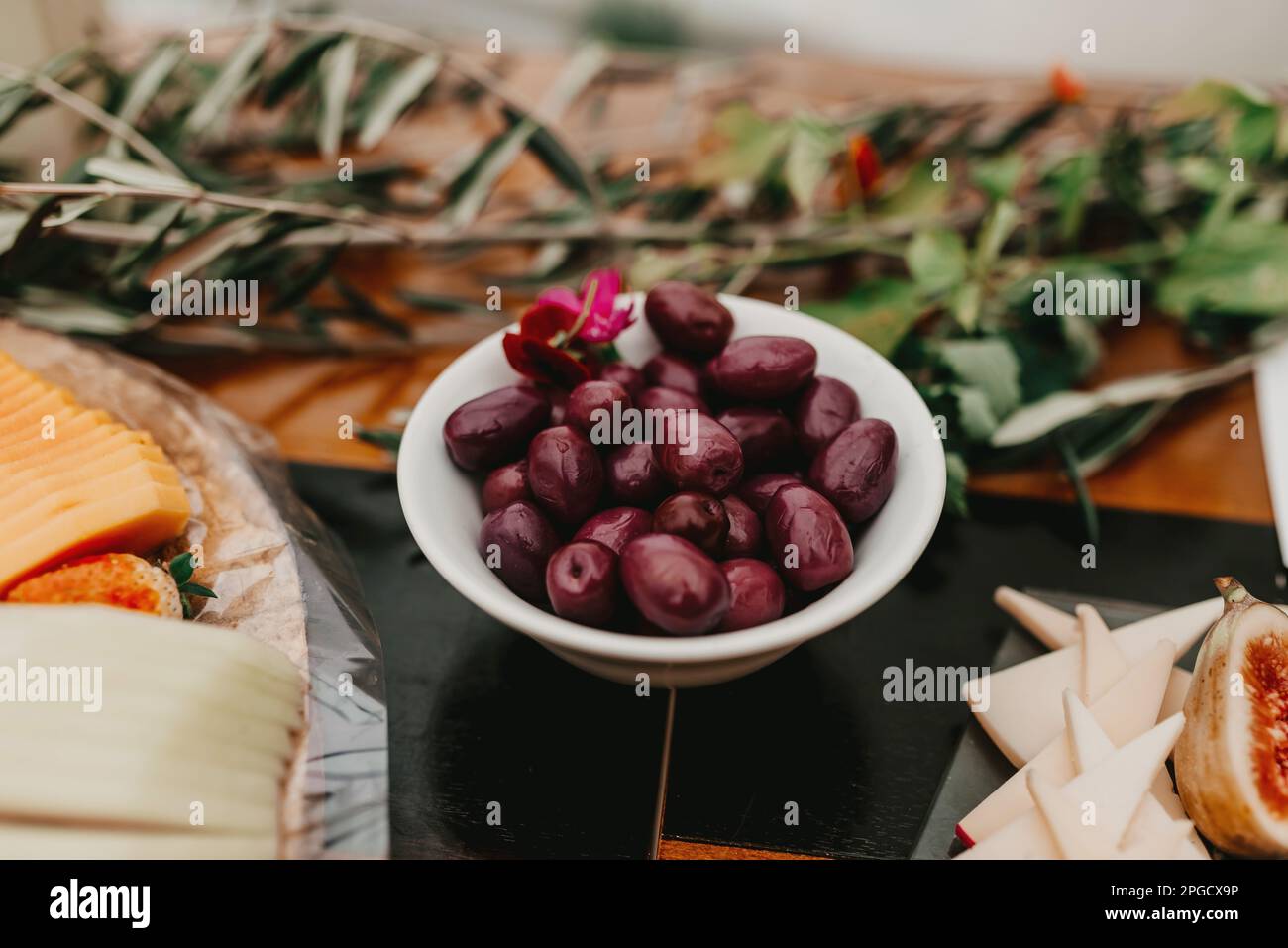 A rustic wooden table displays a variety of snacks, including a plate of juicy grapes, freshly baked bread, and small figurines Stock Photo