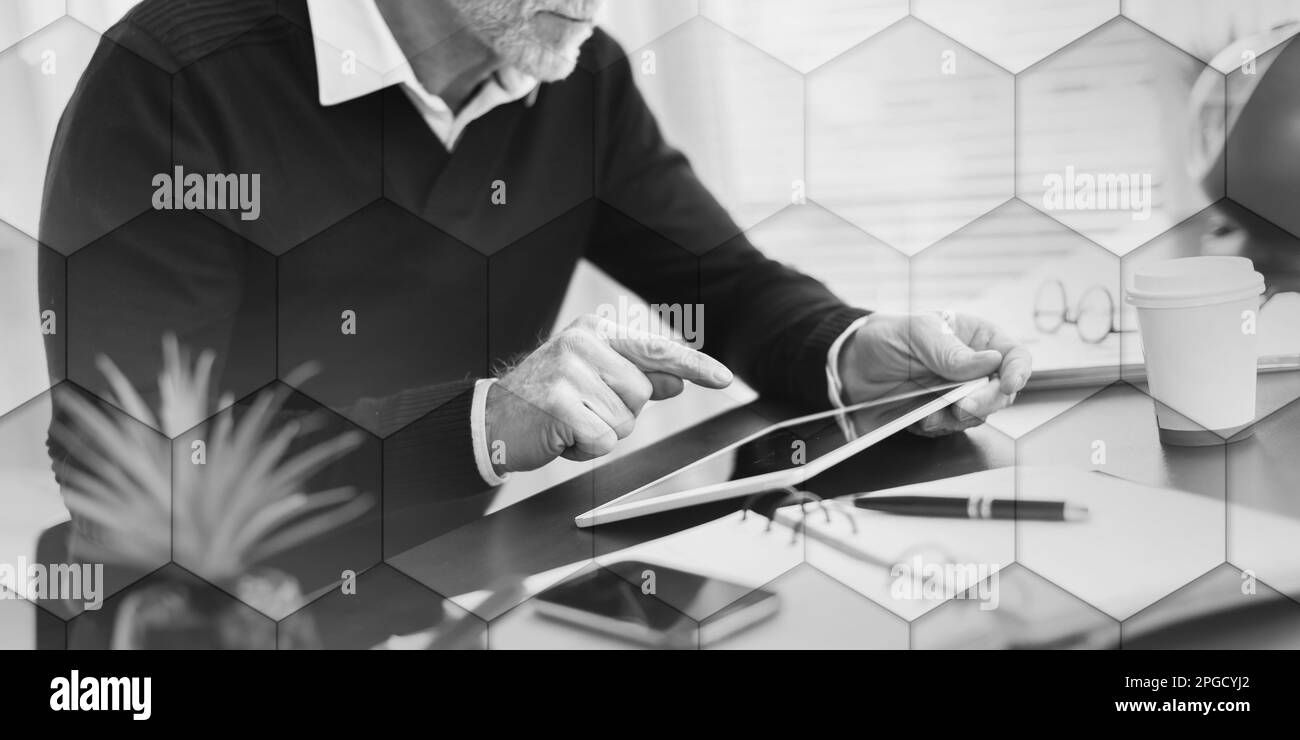 Senior businessman working on digital tablet at office, geometric pattern Stock Photo