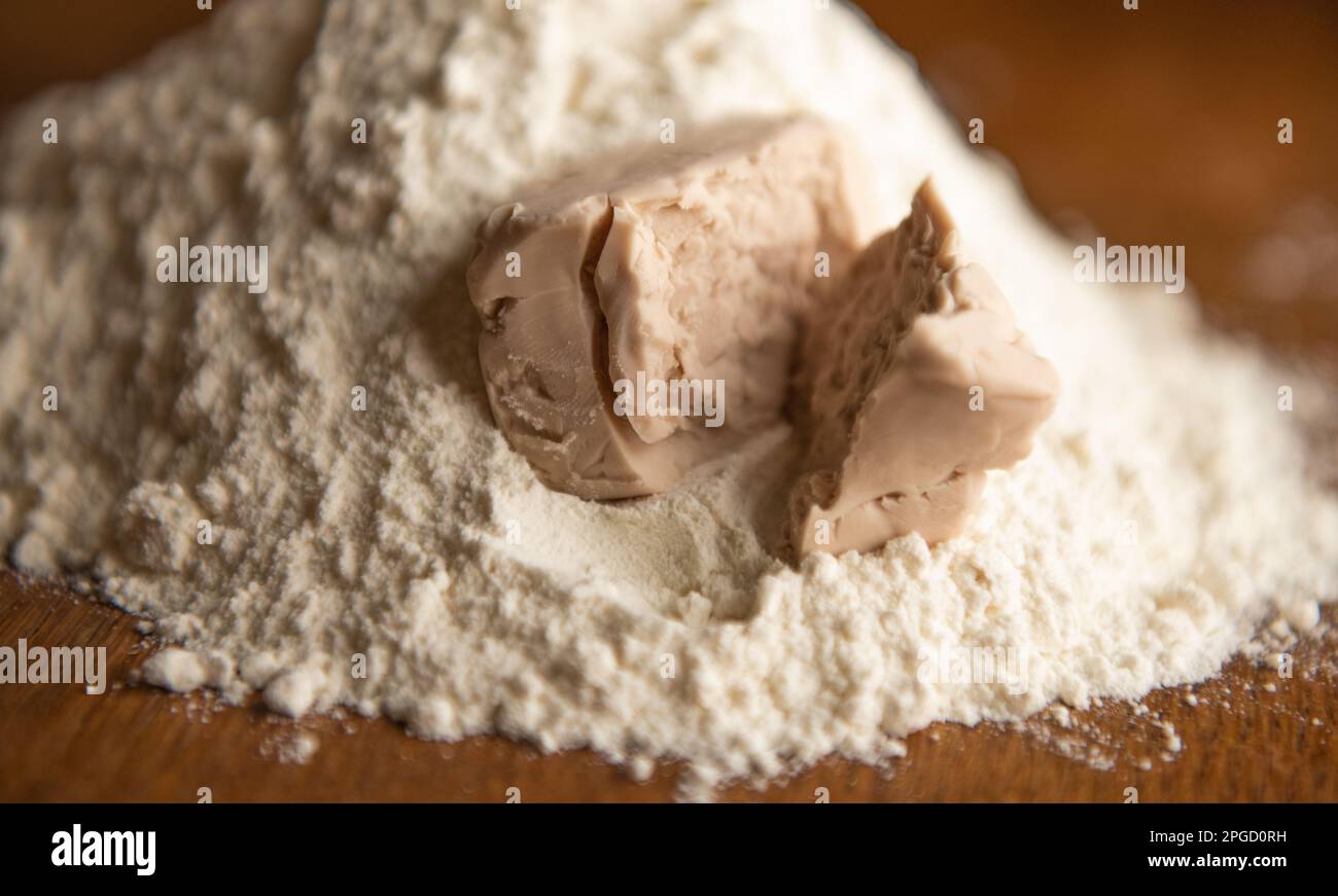 A cube of  yeast crumbled on the flour Stock Photo