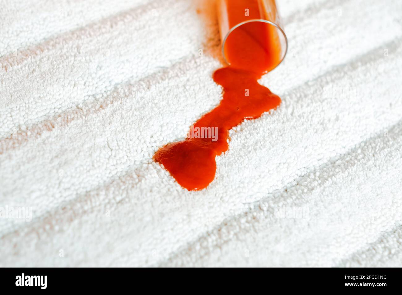 Pouring red juice a glass on a white carpet indoors. closeup. top view. daily life stain concep Stock Photo
