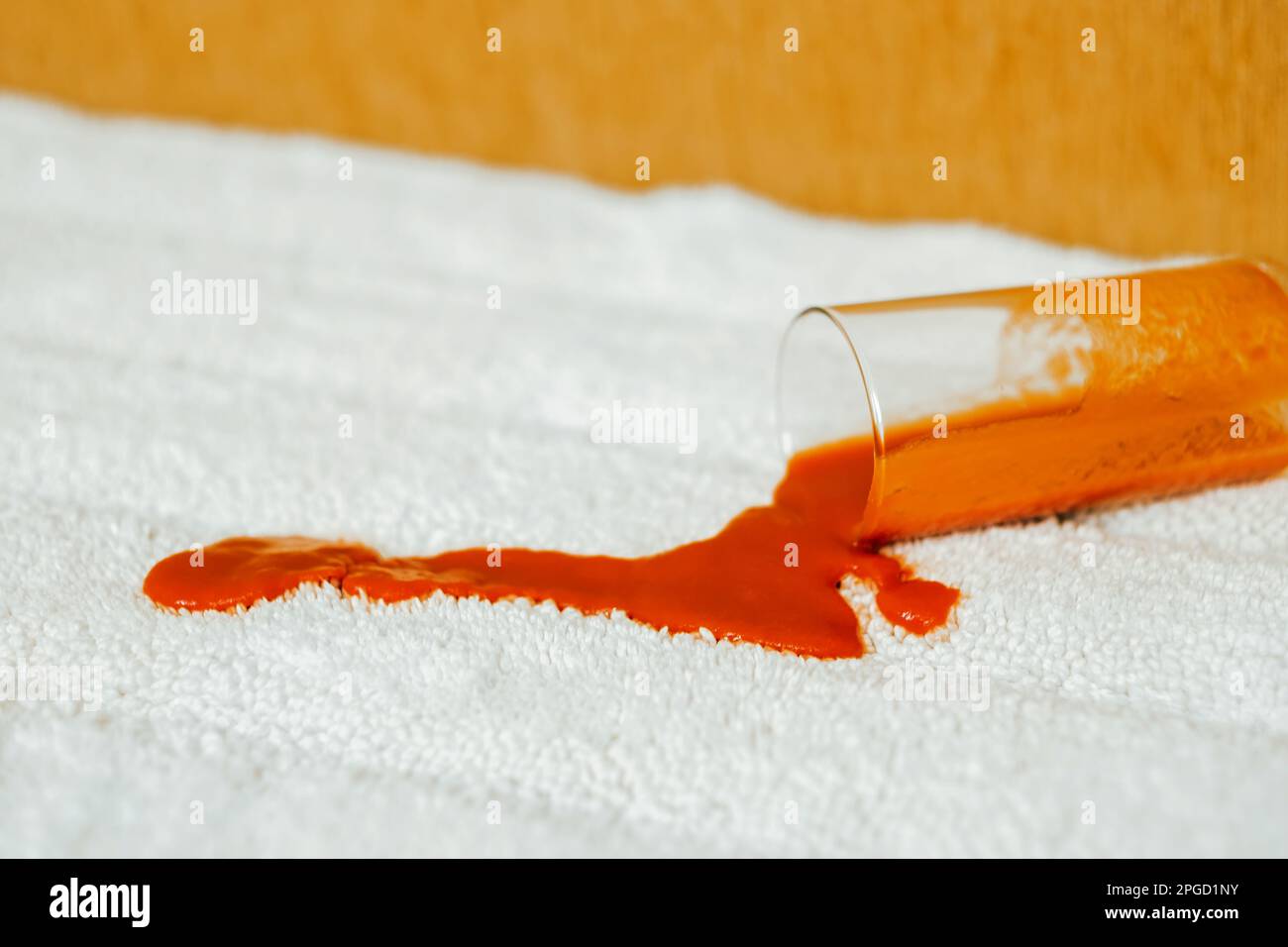 Tomato stain on a white carpet indoors. Spilling juice a glass on the