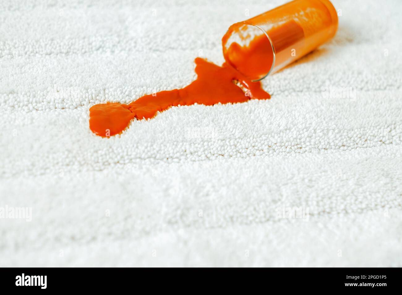 Spilling red juice a glass on a white carpet indoors. closeup. daily life stain concept Stock Photo