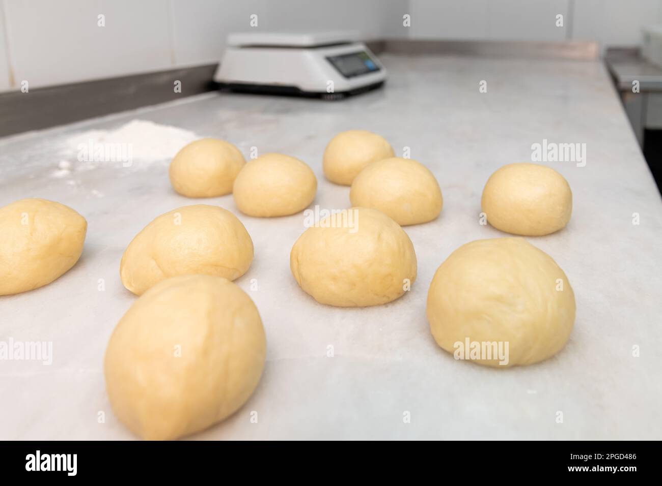 Hamburger bread dough formed into dough balls on a marble counter Stock Photo