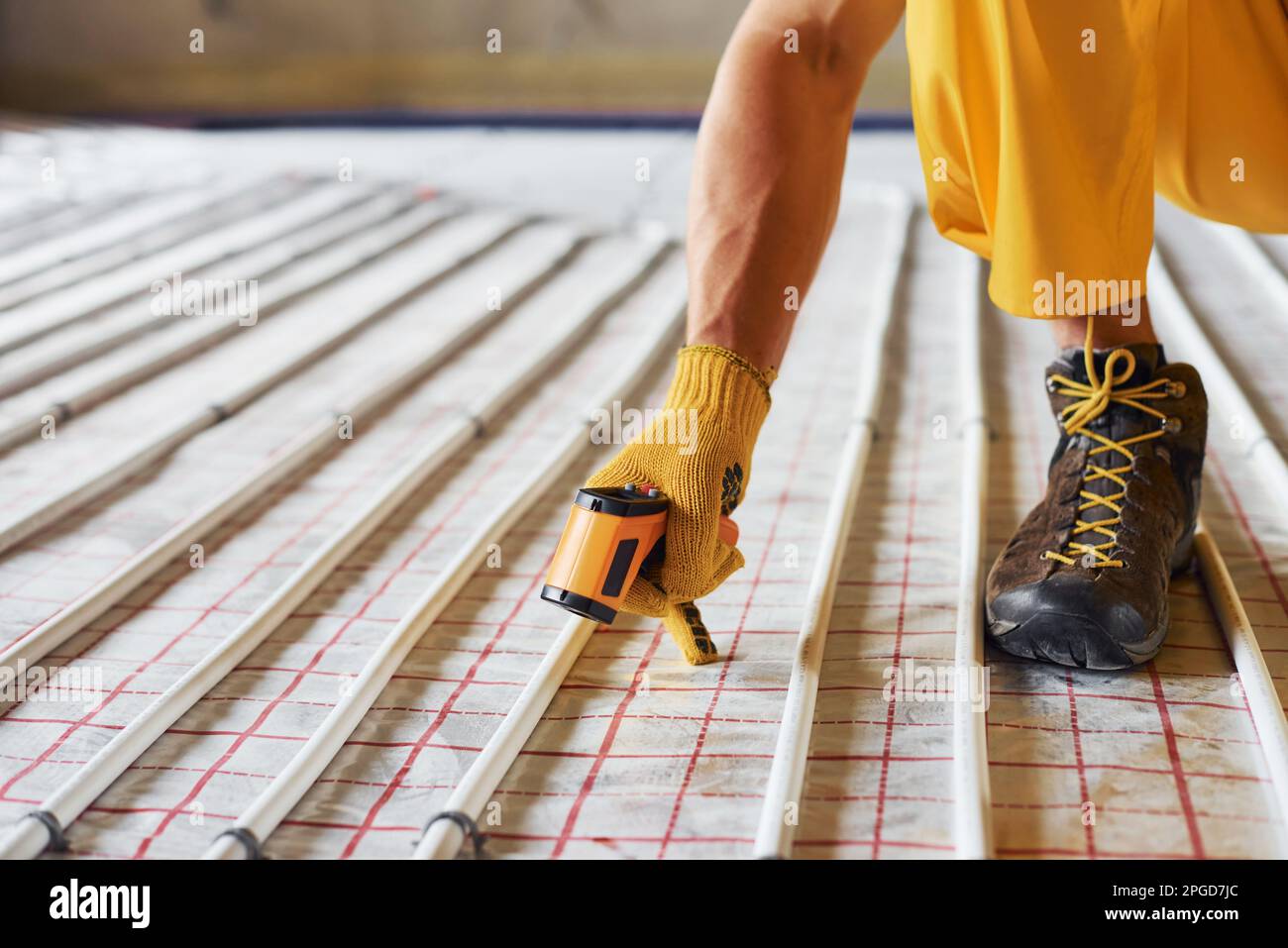 Measures heat of the pipes. Worker in yellow colored uniform installing