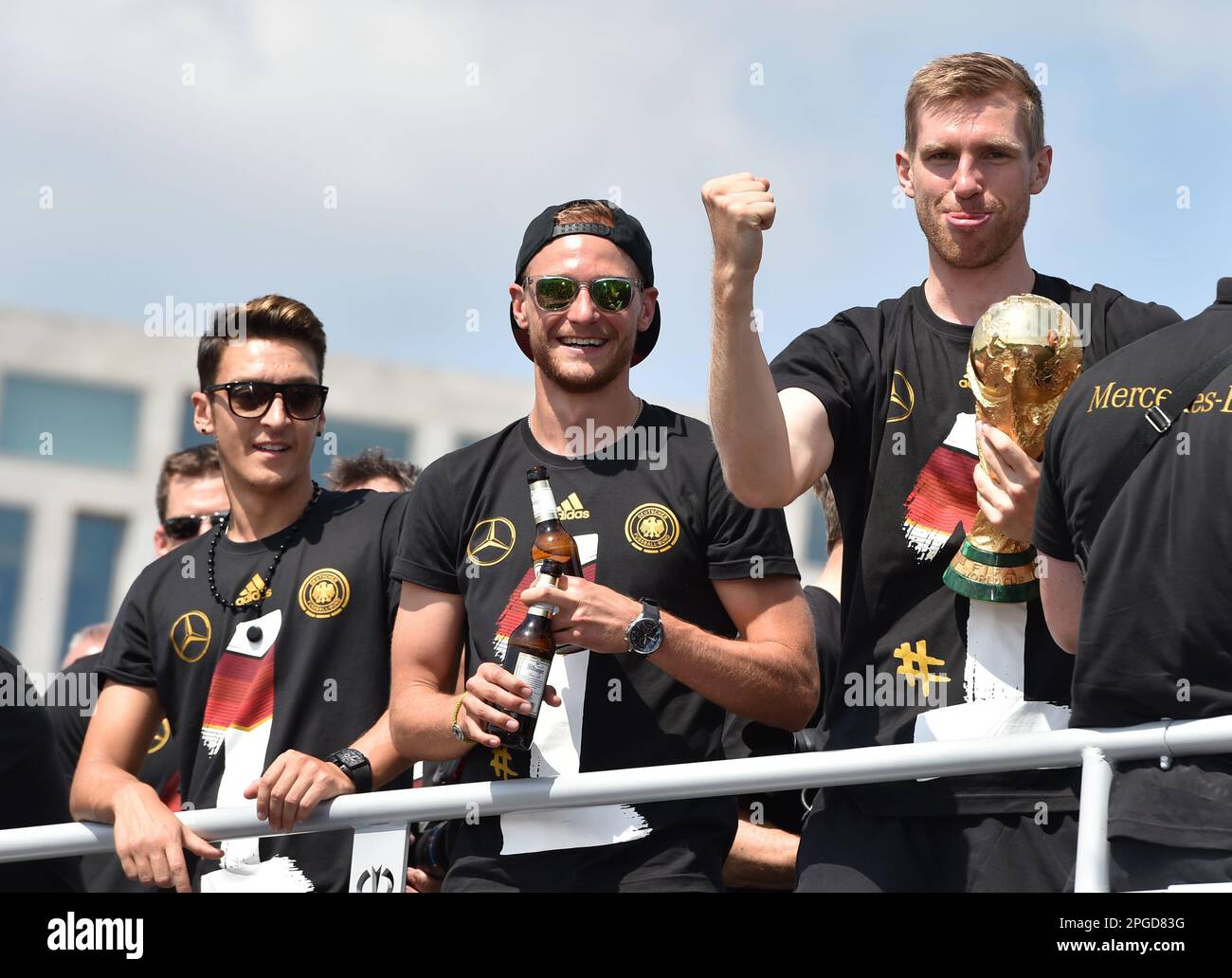 FILED - 15 July 2014, Berlin: National team players Mesut Özil, Benedikt Höwedes and Per Mertesacker (l-r) stand jubilantly with the World Cup trophy in the open team bus at the national soccer team's reception in the capital. After 1954, 1974 and 1990, Germany has become world champion for the fourth time with a victory over Argentina. Former world champion Özil has ended his career as a professional footballer at the age of 34. The 92-time German international announced his immediate retirement Wednesday on his verified profiles on Twitter, Instagram and Facebook. Photo: Jens Kalaene/dpa-Zen Stock Photo