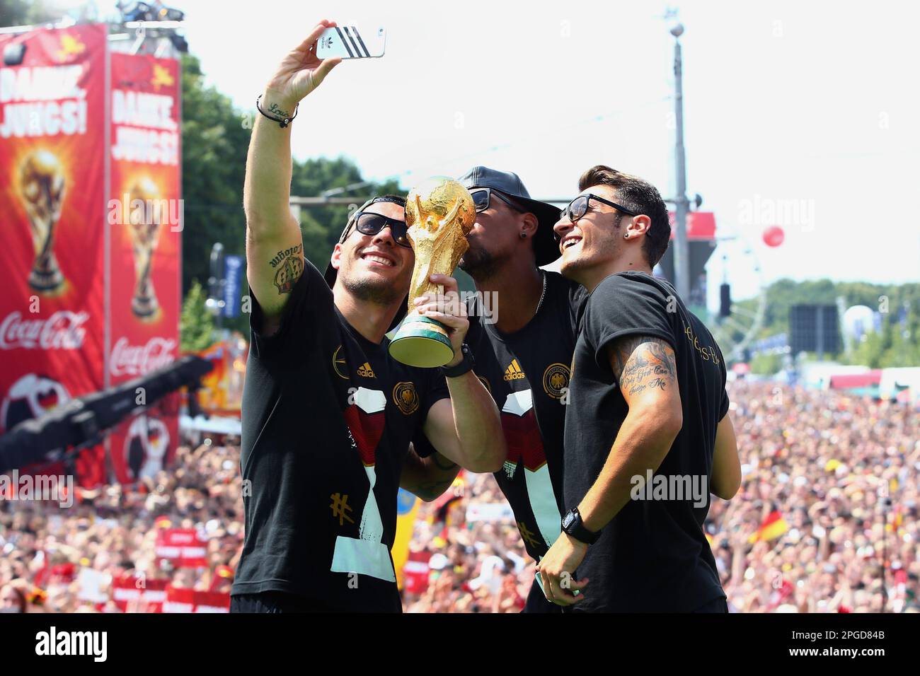 Berlin, Germany. 15th July, 2014. National team players Lukas Podolski (l-r), Jerome Boateng and Mesut Özil celebrate in front of the Brandenburg Gate with the World Cup trophy. Former World Cup winner Özil has ended his career as a professional soccer player at the age of 34. The 92-time international announced his decision on Friday. The 92-time German international announced his immediate retirement on Wednesday on his verified profiles on Twitter, Instagram and Facebook. Credit: Alex Grimm/Bongarts/Pool/dpa/Alamy Live News Stock Photo