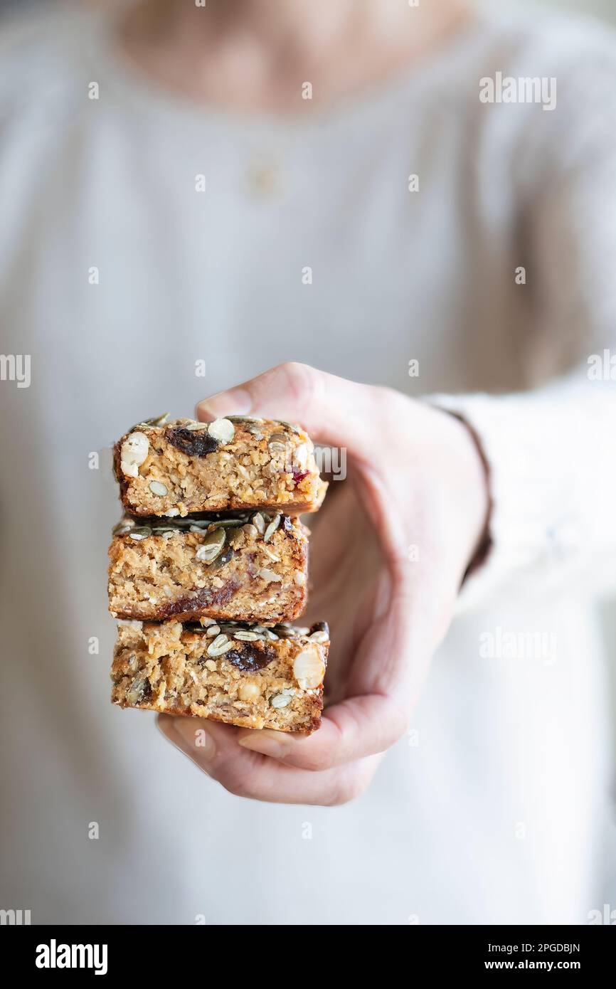 A woman holding three portions of home made flapjack. The flapjack has been baked with assorted fruit and nuts including dates, sultanas and walnuts Stock Photo