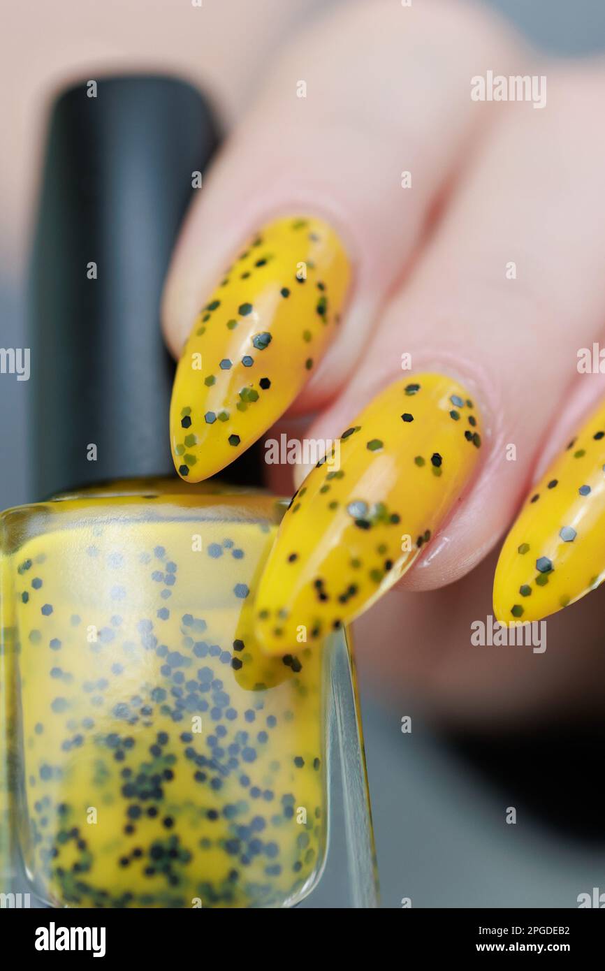 Female beautiful hand with long nails and a yellow and black nail