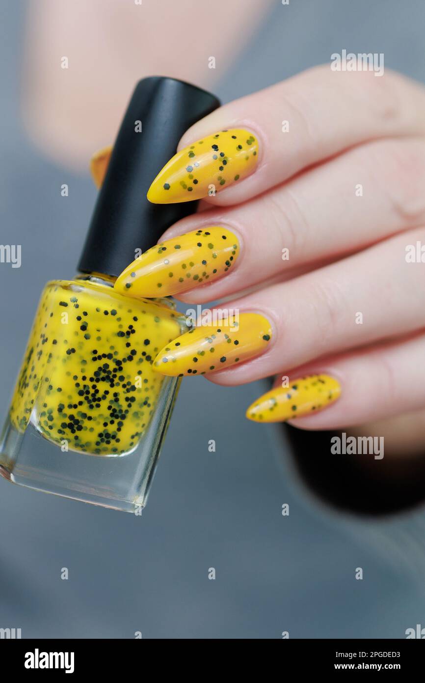 Female beautiful hand with long nails and a yellow and black nail