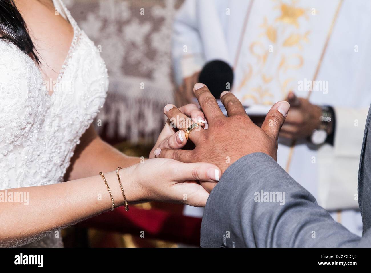 Close up, bride's hands placing wedding ring on her husband on the