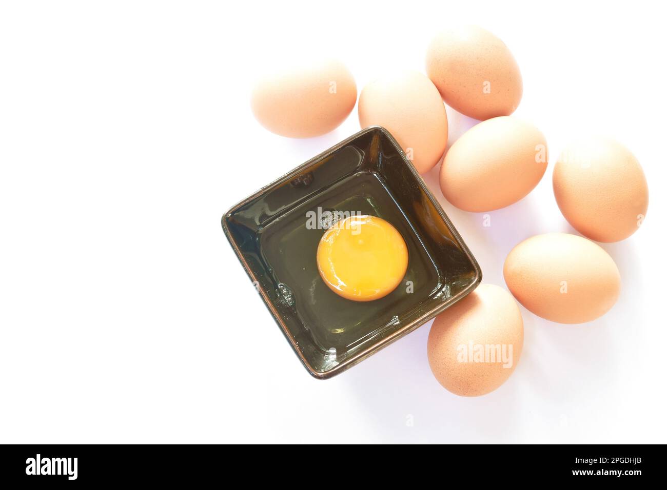 raw yolk and white egg cracked from shell in cup on white background